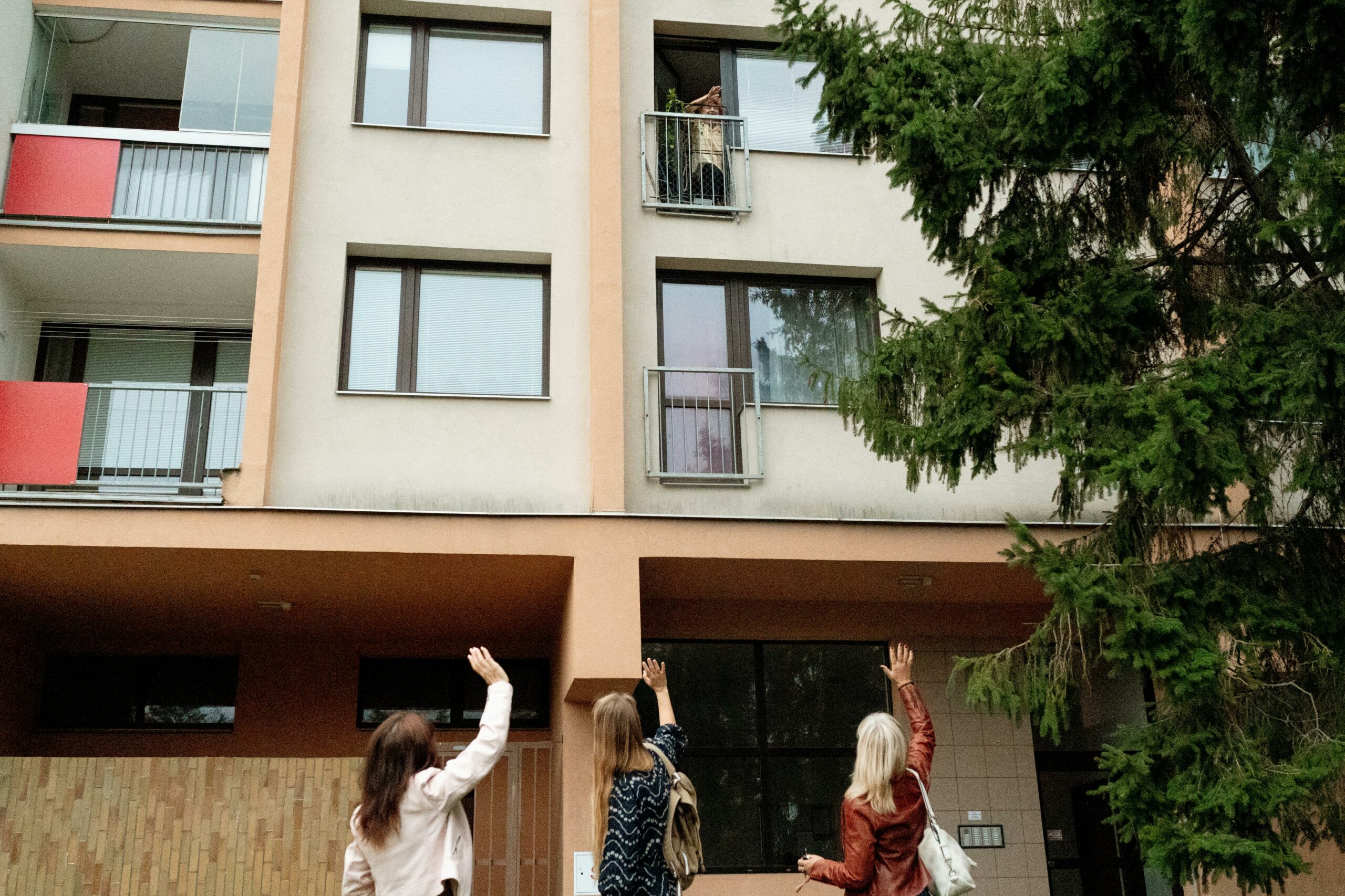Drei Frauen winken einer älteren Dame auf dem Balkon einer Wohnung in Prag zu.