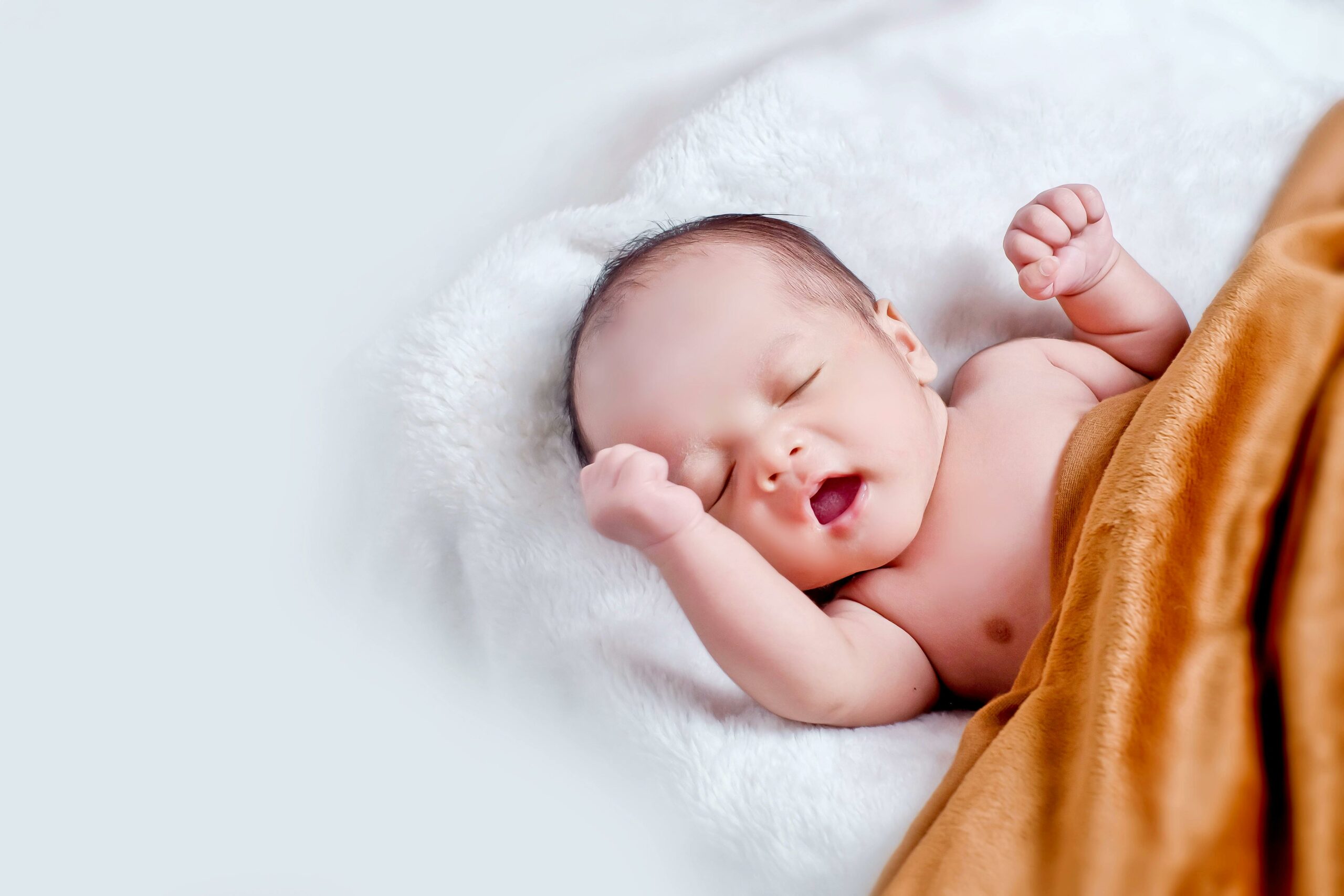 Baby, Das Auf WeiÃŸem Fell Mit Brauner Decke Liegt