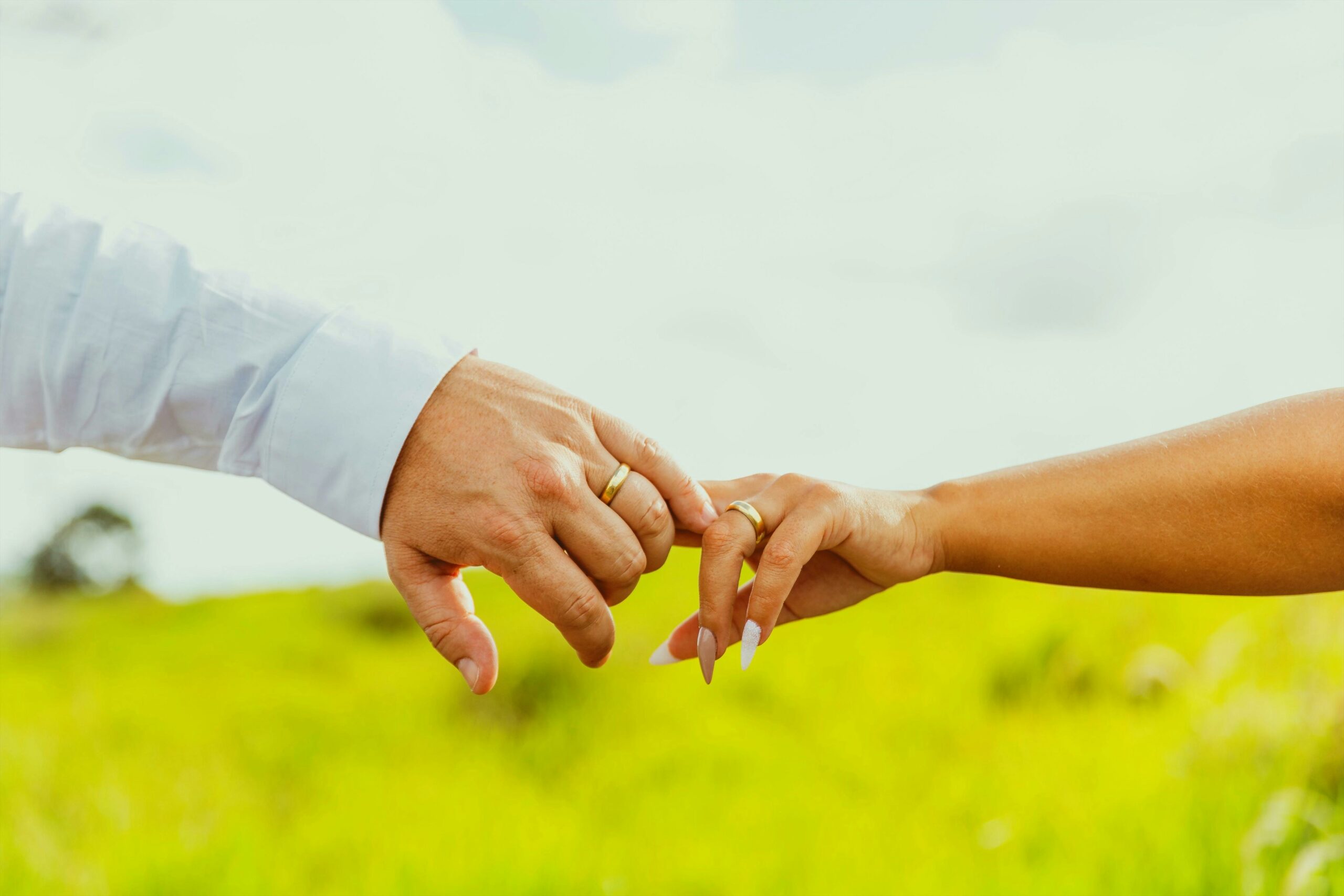 Nahaufnahme eines Paares, das auf einem sonnigen Feld HÃ¤ndchen hÃ¤lt und Liebe und Verbundenheit symbolisiert.