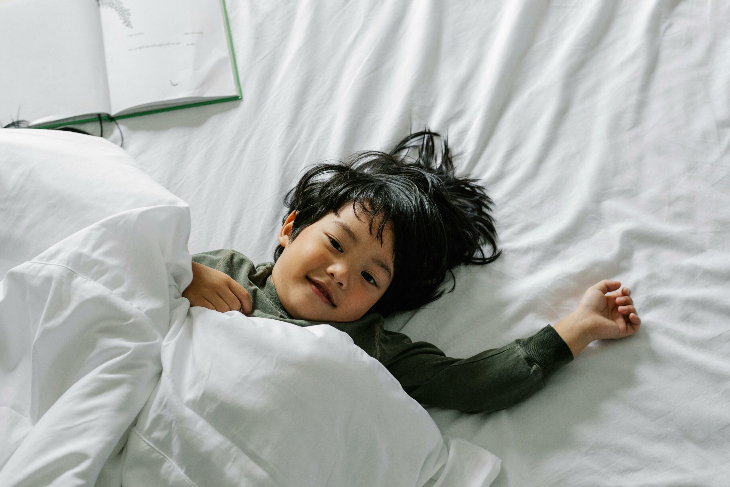 Ethnischer Junge, Der Nach Dem Schlafen Im Bett Liegt